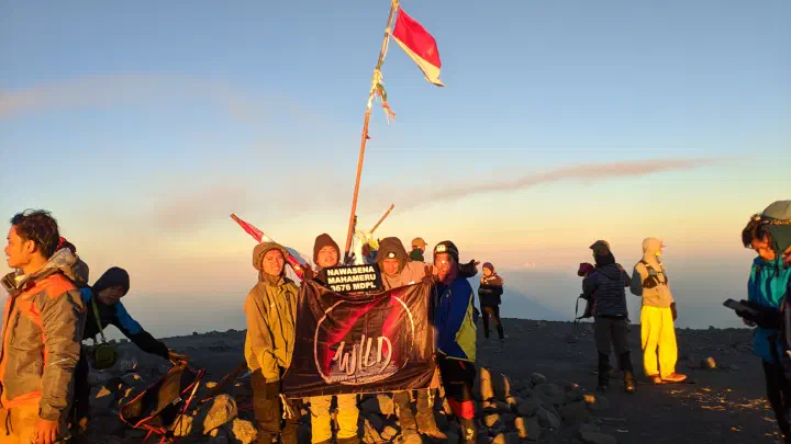 Saya bersama teman-teman berfoto dengan membawa papan nama bertuliskan &ldquo;NAWASENA Mahameru 3676 MDPL&rdquo; dengan latar belakang bendera Merah Putih yang berada di Puncak Mahameru